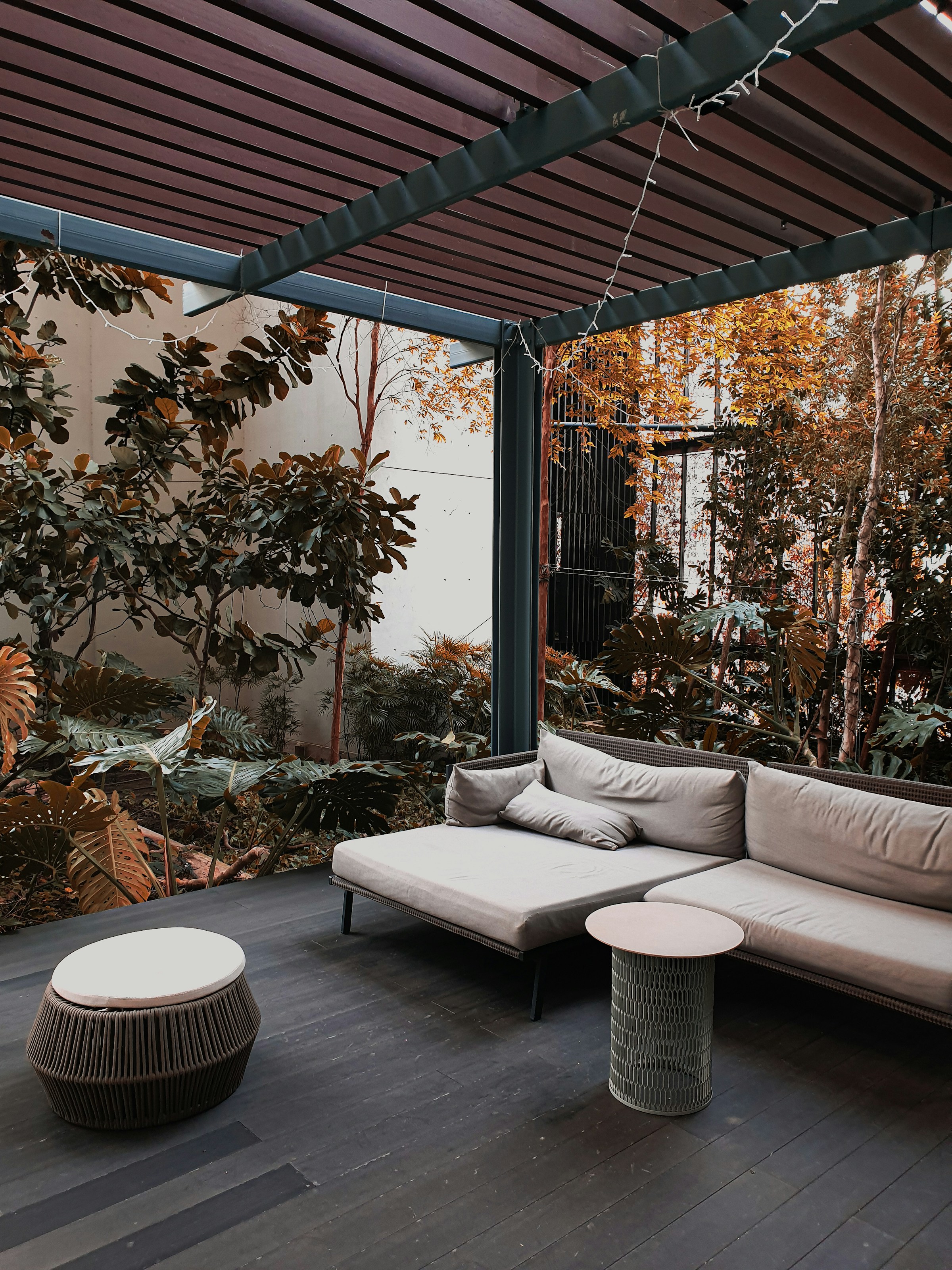 Covered patio with an outdoor sofa, lounge chairs, and planters
